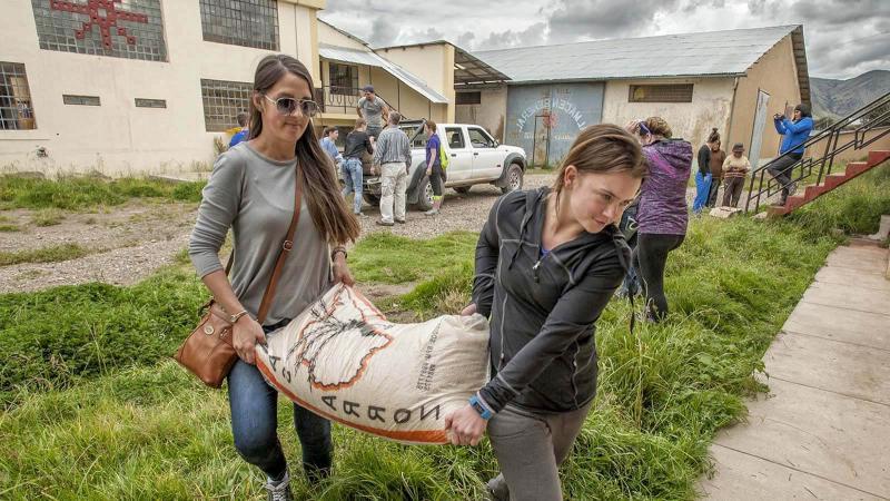 Two female volunteers in Peru delivering bags of rice.